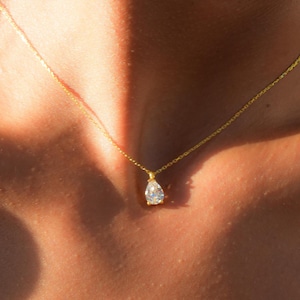 May include: A gold chain necklace with a teardrop-shaped diamond pendant.