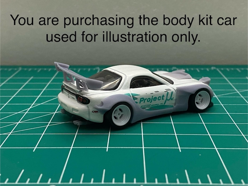 K&ouml;nnte beinhalten: Wei&szlig;es Modellauto mit gro&szlig;em Heckfl&uuml;gel, breiten Reifen und "Project &mu;" Schriftzug an der Seite. Das Auto steht auf einer gr&uuml;nen Schneidematte.