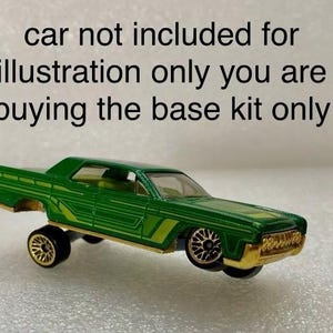 May include: Green die-cast car model with gold accents. The car is missing wheels and is floating in the air. The text "car not included for illustration only you are buying the base kit only" is written above the car.