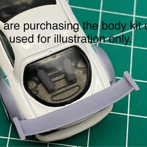 K&ouml;nnte beinhalten: Ein wei&szlig;er Karosserie-Kit f&uuml;r ein Auto mit einem Heckspoiler. Der Kit besteht aus glattem, hellgrauem Kunststoff. Der Text "You are purchasing the body kit car used for illustration only." ist im Bild sichtbar.