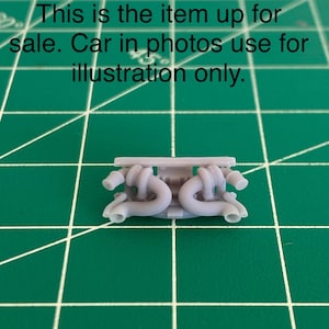 May include: A miniature, pale grey car engine part, possibly a turbocharger or exhaust manifold, featuring complex, curved pipes and connectors. The image text states: "This is the item up for sale. Car in photos use for illustration only."