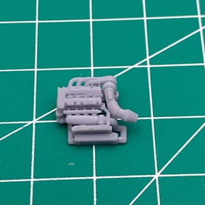 May include: A detailed plastic model of a car engine in a light purple colour. The engine has a variety of pipes and hoses attached to it.