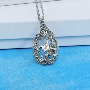 May include: A silver necklace with a wire-wrapped pendant featuring a dragon design.