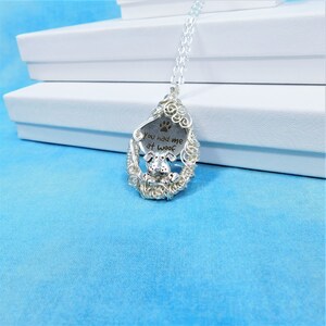May include: Silver necklace with a wire-wrapped pendant featuring a dog paw print and the text "You had me at woof".