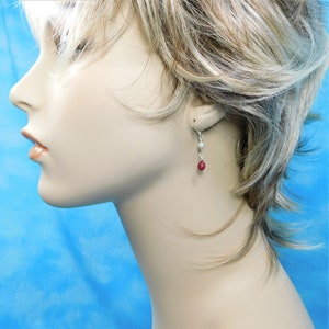 May include: Silver dangle earrings with a red gemstone and two white pearls.