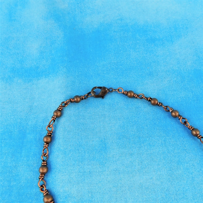 K&ouml;nnte beinhalten: Eine Halskette aus Kupferkette mit einem Karabinerverschluss. Die Kette besteht aus kleinen, runden Perlen.