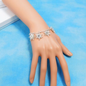 May include: A silver bracelet featuring several star-shaped charms. The charms are crafted from silver wire and have a sparkling finish.