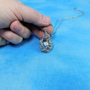 May include: Silver necklace with a wire-wrapped pendant featuring a dragon design.