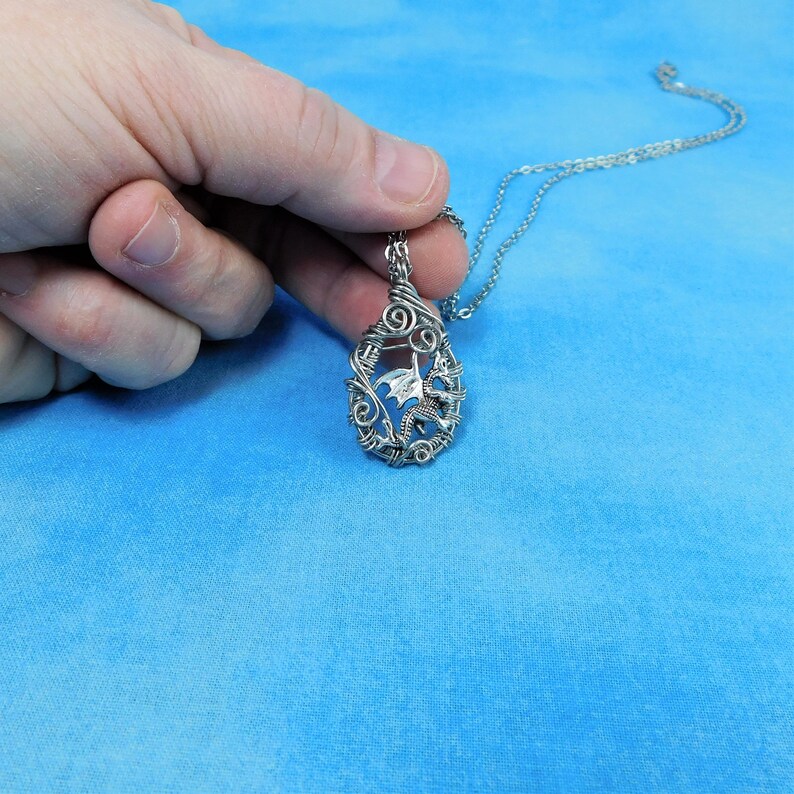 May include: Silver necklace with a wire-wrapped pendant featuring a dragon design.