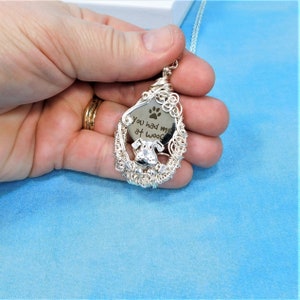 May include: Silver wire wrapped pendant with a silver disc featuring a paw print and the text "You had me at woof".