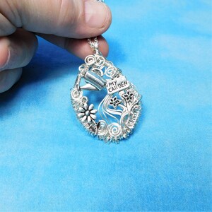 Pode incluir: Pingente de fio de prata com um regador, flores e uma placa que diz "Meu jardim".