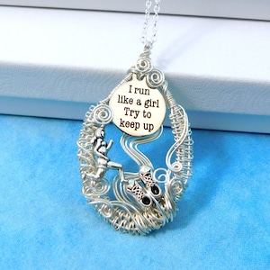 May include: Silver wire wrapped pendant necklace featuring a running woman and running shoes. The pendant has a round disc with the text "I run like a girl Try to keep up".