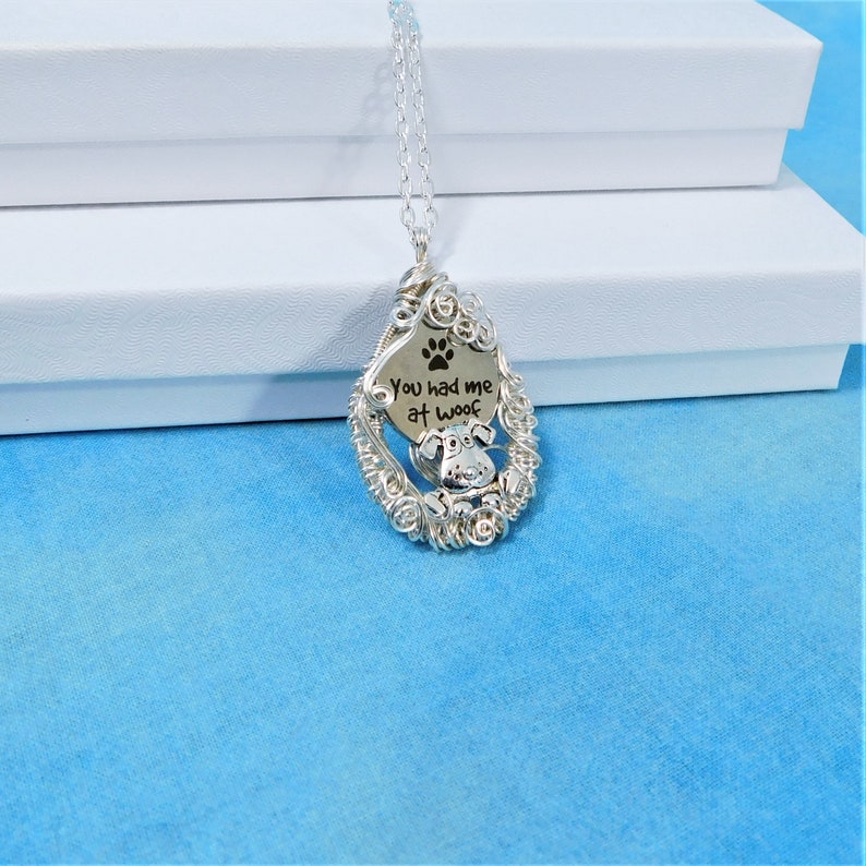 May include: Silver necklace with a wire-wrapped pendant featuring a paw print and the text "You had me at woof".
