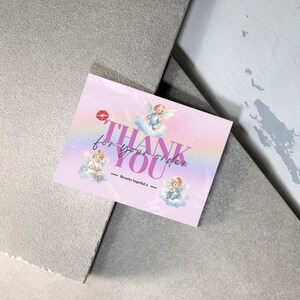 May include: Pink thank you card with a rainbow and three cherubs. The card says "Thank you for your order - Beauty Angels LA."