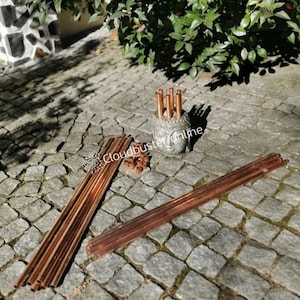 Peut inclure: Un ensemble de tuyaux en cuivre, certains disposés dans un support en forme de tête de Bouddha, et d'autres disposés sur un patio en pierre. Les tuyaux sont utilisés pour un chasse-nuages, un appareil utilisé dans le travail énergétique de l'orgonite.