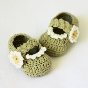 May include: A pair of green crocheted baby shoes with white and yellow daisy embellishments.
