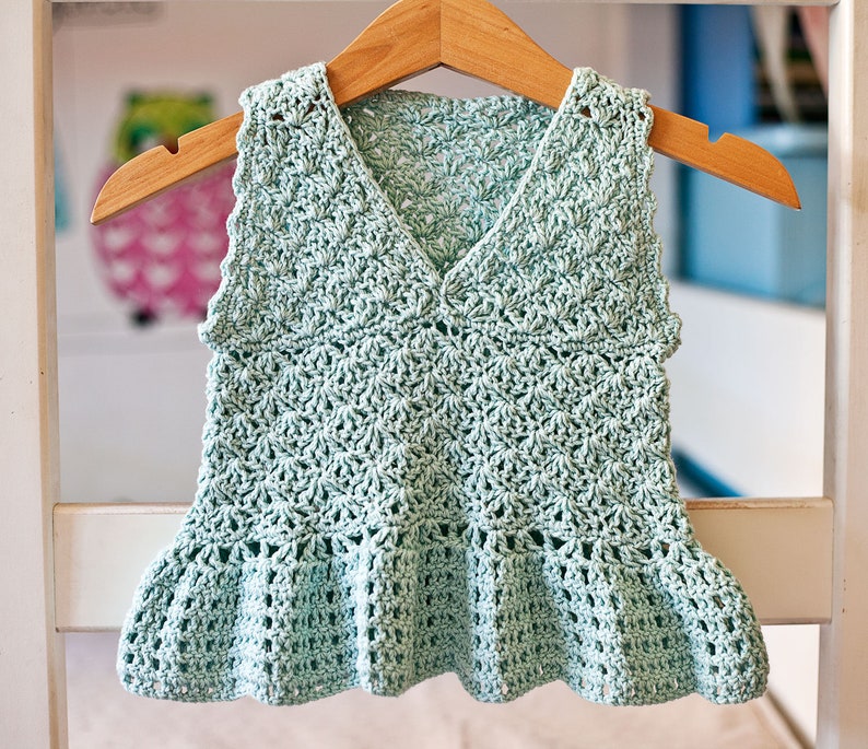 May include: A light green crocheted sleeveless top with a ruffled hem.