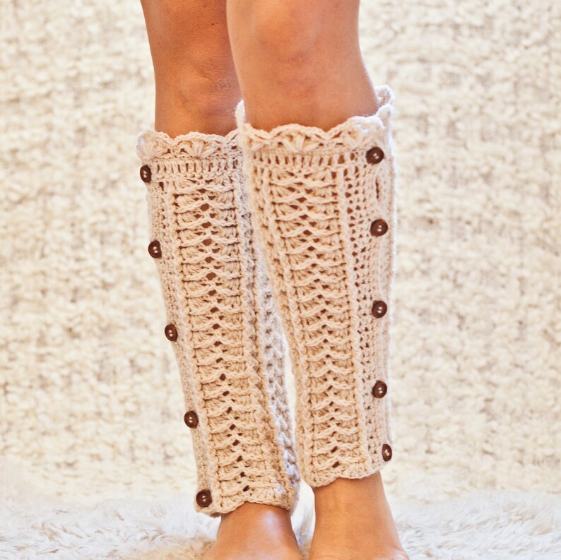 May include: A pair of cream-colored crocheted leg warmers with a scalloped top and brown buttons down the side.