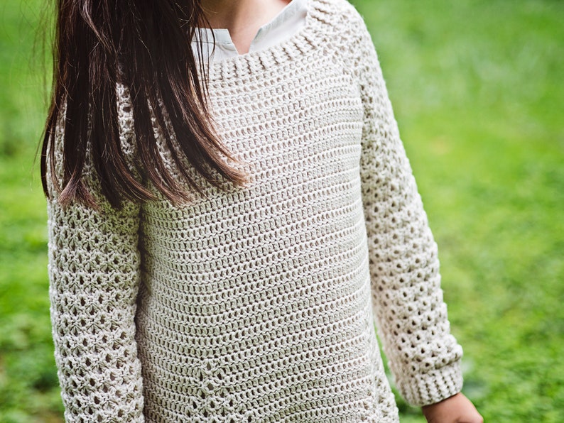 K&ouml;nnte beinhalten: Ein hellbeige H&auml;kelpullover mit langen &Auml;rmeln. Der Pullover hat einen runden Ausschnitt und ein strukturiertes, offen gewebtes Design. Die &Auml;rmel haben ein offeneres, spitzenartiges Muster. Der Pullover ist aus weichem, nat&uuml;rlich aussehendem Garn gefertigt.