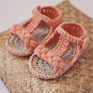 Puede incluir: Un par de sandalias de crochet en color melocot&oacute;n y beige. Las sandalias tienen un dise&ntilde;o de correa trenzada y un detalle de bot&oacute;n.