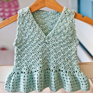 May include: A light green crocheted sleeveless top with a ruffled hem.