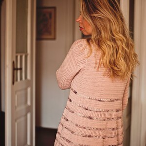 Peut inclure: Un cardigan en crochet rose avec un motif ray&eacute; et une coupe ample.