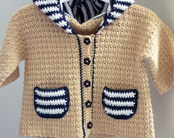 May include: A tan crocheted hooded cardigan with blue and white striped trim and pockets. The cardigan has a button closure.