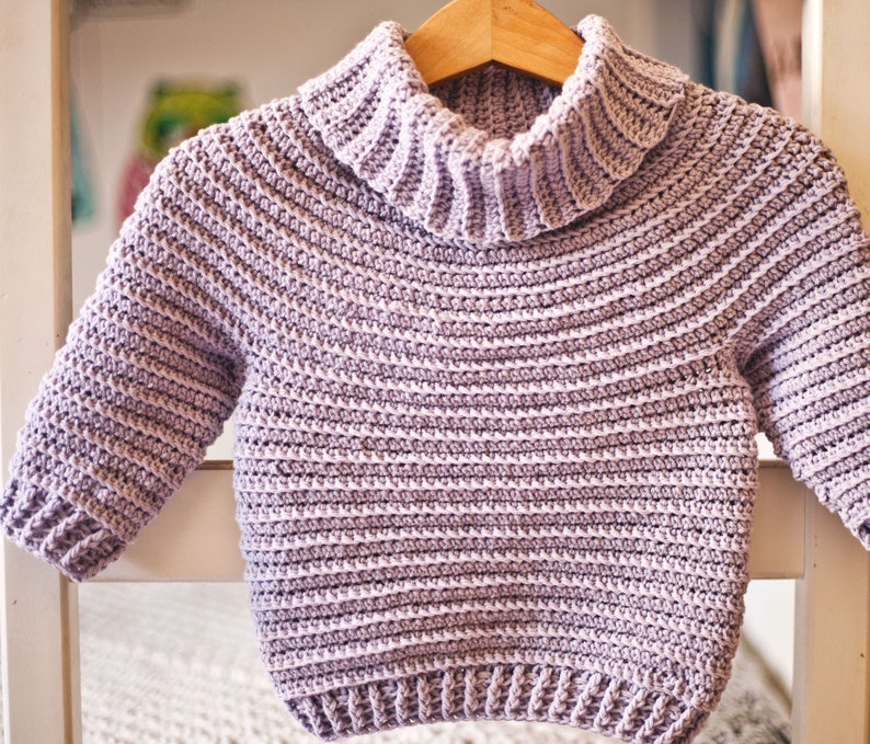 May include: A light purple crocheted sweater with a turtleneck and long sleeves.