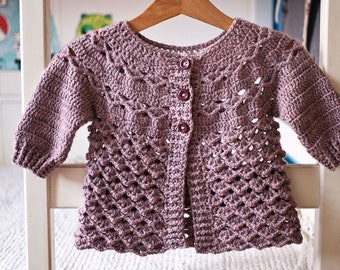 Op de afbeelding: Een gehaakt vest in mauve kleur met knoopsluiting. Het vest heeft een kantpatroon en een gegolfde zoom.