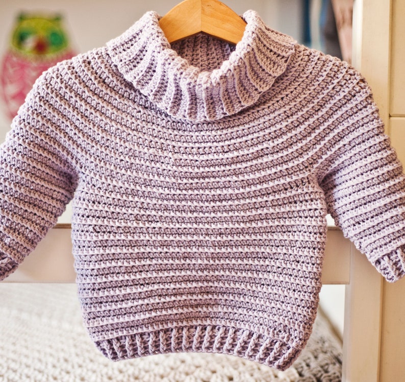 May include: A light purple crocheted sweater with a turtleneck and long sleeves.