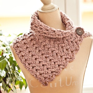 Può includere: Un collo in crochet rosa con chiusura a bottone. Il collo è esposto su un manichino bianco.