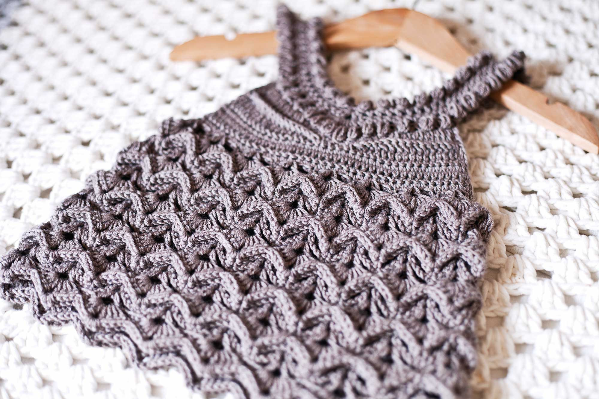 May include: A brown crocheted halter top with a textured pattern. The top is hanging on a wooden hanger.