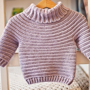 May include: A light purple crocheted sweater with a turtleneck and long sleeves.