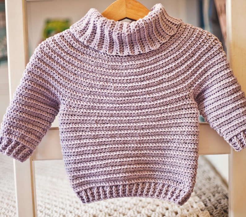 May include: A light purple crocheted sweater with a turtleneck and long sleeves.
