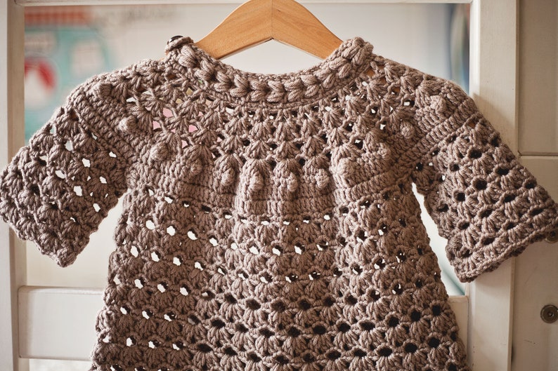 Puede incluir: Un su&eacute;ter de ganchillo marr&oacute;n con un patr&oacute;n de encaje y un escote redondo. El su&eacute;ter tiene un dise&ntilde;o texturizado con peque&ntilde;as bolitas en todas partes.