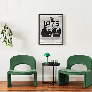 May include: Two green velvet chairs with a black side table and a green lamp in between. A black and white poster of the band "The 1975" hangs on the wall behind the table.