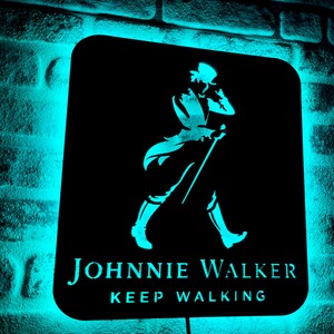 May include: A black metal sign with a blue neon glow. The sign features a silhouette of a man walking with a cane and the text "JOHNNIE WALKER KEEP WALKING."