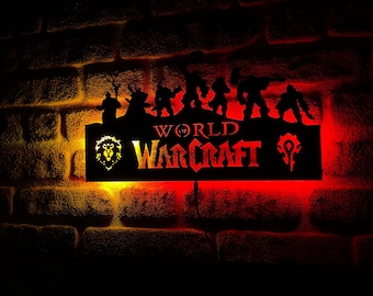 Puede incluir: Un letrero de metal negro con una silueta de personajes del videojuego World of Warcraft. El letrero está iluminado desde atrás con luces rojas y amarillas. El texto "WORLD OF WARCRAFT" es visible en el letrero.