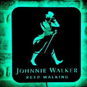 May include: A black and green neon sign with the Johnnie Walker logo. The logo features a man in a top hat walking with a cane. The text "Keep Walking" is below the logo.