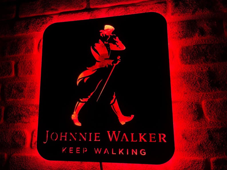 May include: A black metal sign with a red glow behind it. The sign features a silhouette of a man walking with a cane and the text "JOHNNIE WALKER KEEP WALKING".