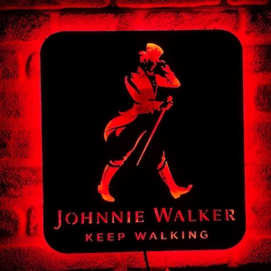 May include: A red neon sign with a black background featuring a silhouette of a man in a top hat and the text "JOHNNIE WALKER KEEP WALKING".
