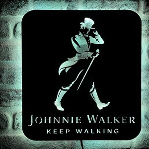 May include: Black and white silhouette of a man walking with a stick, with the text "JOHNNIE WALKER KEEP WALKING" below.