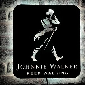 May include: A black and white sign with the Johnnie Walker logo. The logo features a man in a top hat walking with a cane. The text "Keep Walking" is below the logo.
