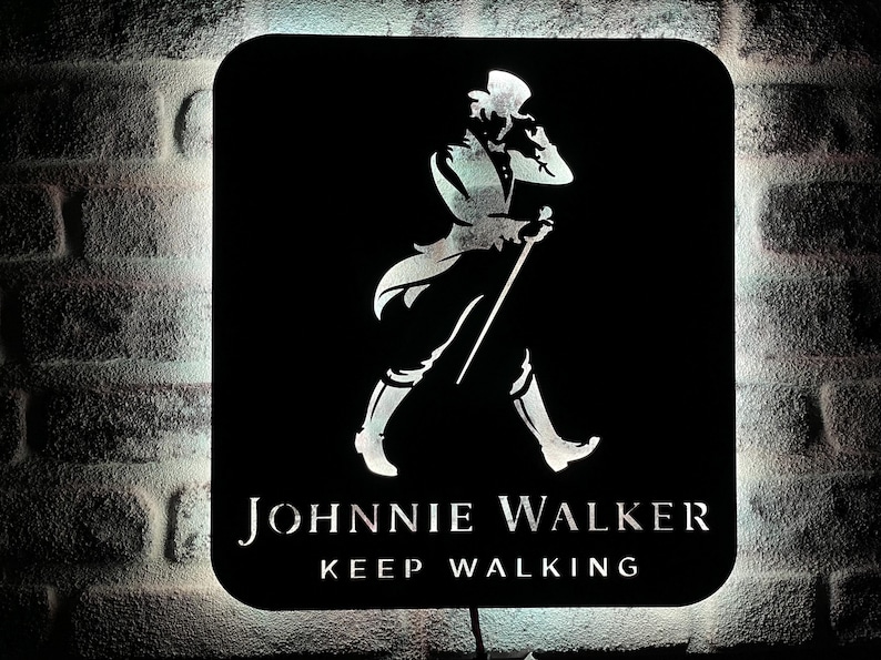 May include: A black and white sign with the Johnnie Walker logo. The logo features a man in a top hat walking with a cane. The text "Keep Walking" is below the logo.
