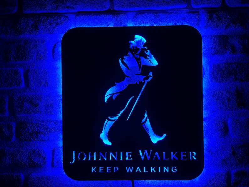 May include: A black and blue illuminated sign with the Johnnie Walker logo. The logo features a man in a walking pose with a cane. The text "Keep Walking" is below the logo.