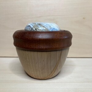 May include: A wooden box with a lid made of a light blue and white marbled stone. The box is made of light wood with a dark brown rim around the top.