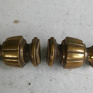 May include: Two antique brass door knobs with a decorative, fluted design. The knobs are separated and facing each other.