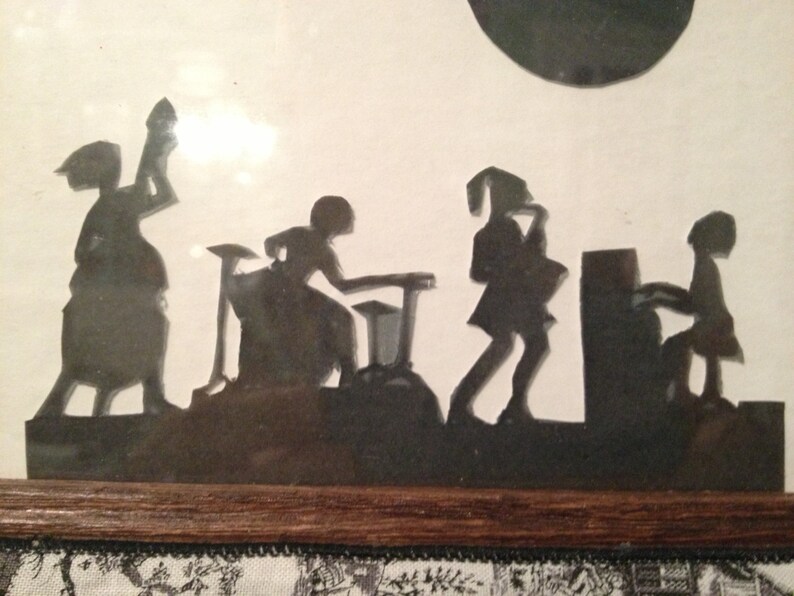 May include: Black silhouette artwork of a band playing music. The band consists of four figures: a drummer, a guitarist, a saxophonist, and a pianist. The artwork is framed and displayed on a wall.