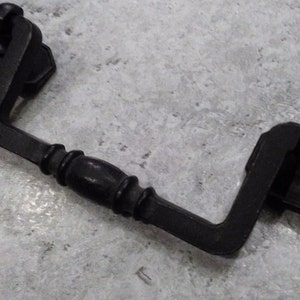 May include: Black metal drawer pull with a curved design. The pull has a rounded knob on each end.