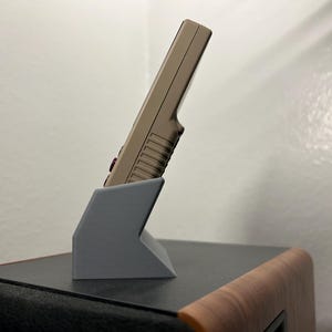 Miyoo Mini plus handheld gaming device shown in the gray dock, showing the aesthetic angle from the side.